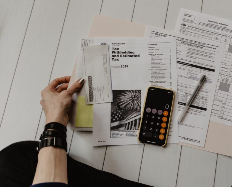 person holding paper near pen and calculator
